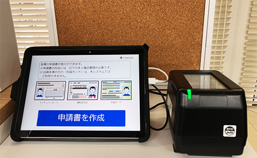「書かない窓口ソリューション」の申請書作成支援システムの端末。タブレットには「申請書を作成」のボタンが大きく表示されている。